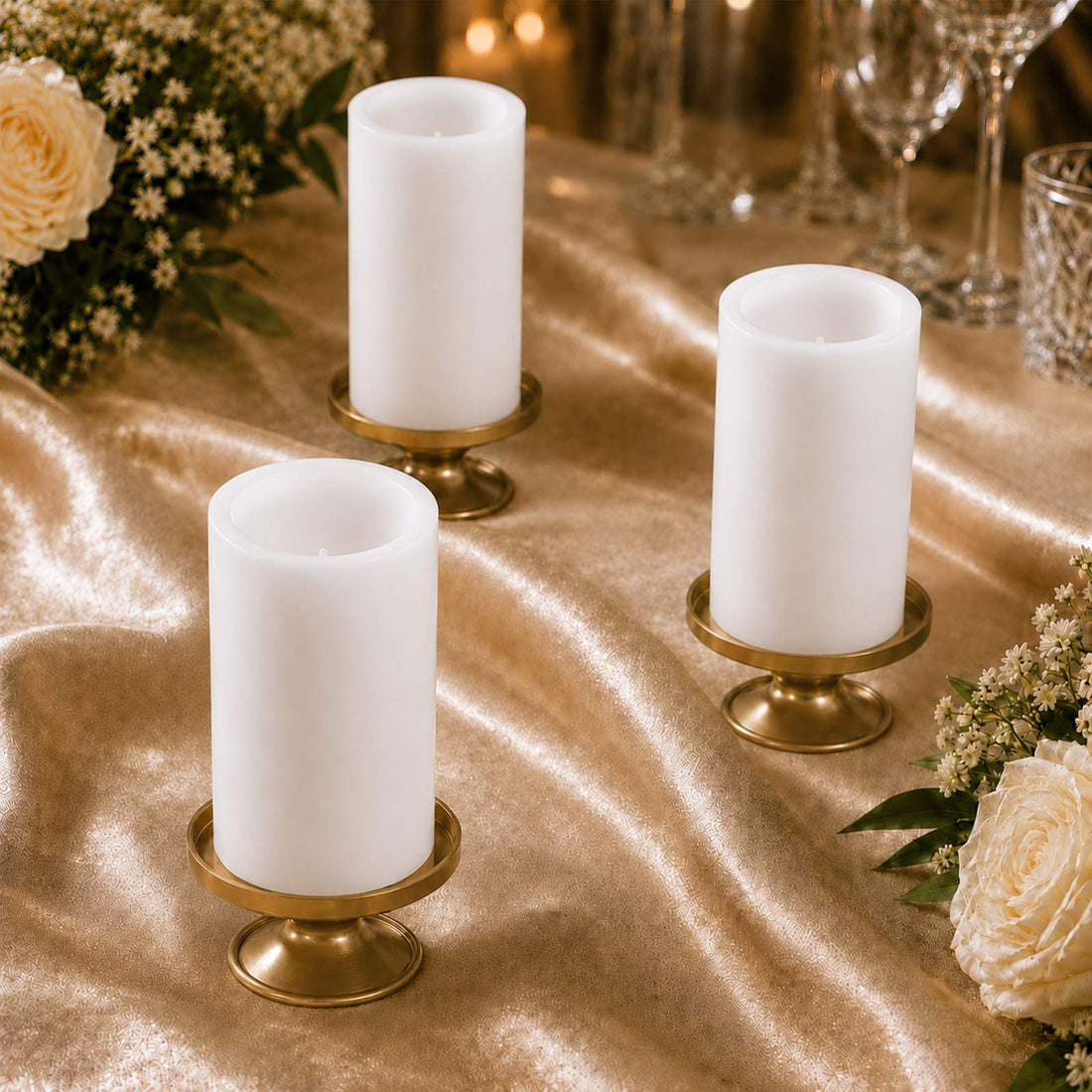 Elegant white pillar candles in gold holders on a gold table setting with flowers