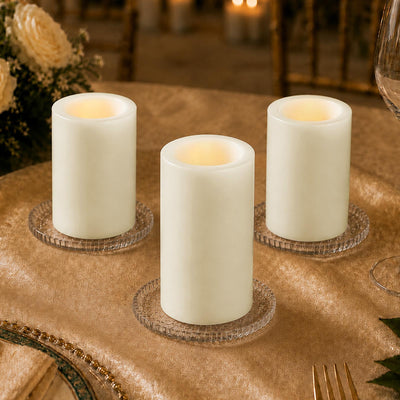 Three flameless LED pillar candles on decorative glass coasters on a table