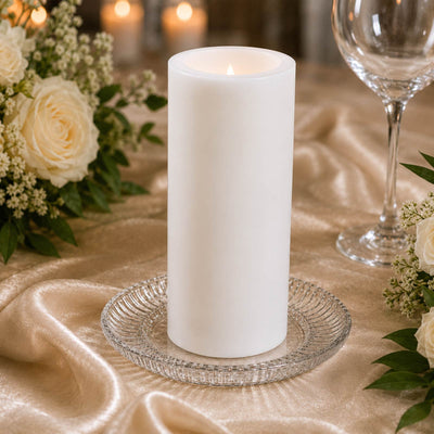 White pillar candle on elegant gold table setting with roses and glassware