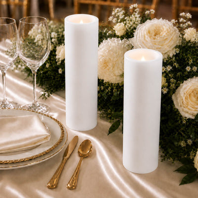 Elegant white pillar candles with floral wedding table centerpiece and gold tableware