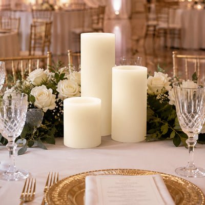 Elegant wedding table centerpiece with white candles, roses, and gold accents