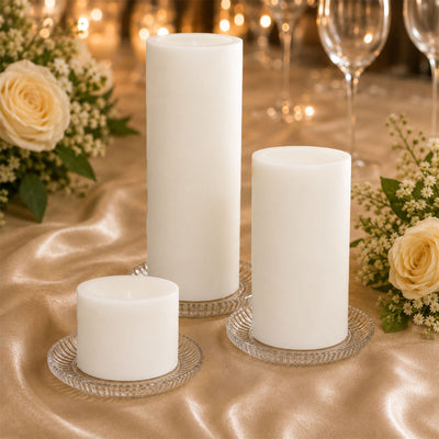Elegant white pillar candles on gold table with roses and glassware