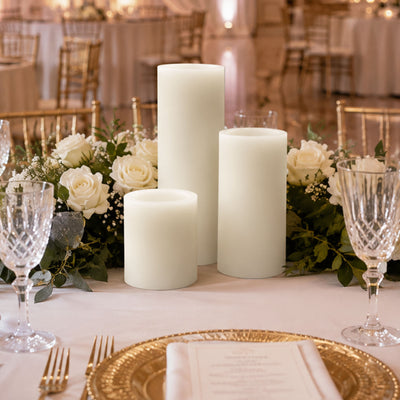 Elegant wedding table centerpiece with white pillar candles and roses