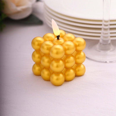 Gold decorative candle in a cube shape with a flickering flame.