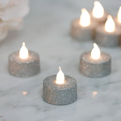 Glittering silver LED tea lights on a marble surface.