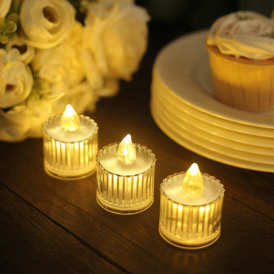 LED flickering tea light candles on a wooden table with flowers and dessert.
