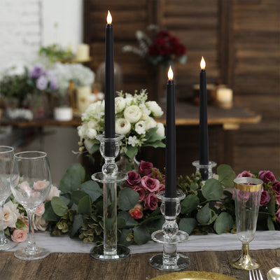 Elegant black taper candles in glass holders with floral wedding table decor