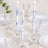 Blue floral candles in glass holders on a dining table setting.