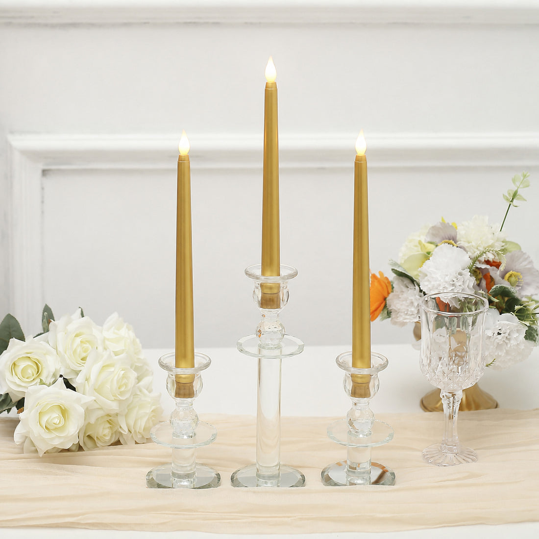 Elegant gold LED taper candles in glass holders with white floral centerpiece