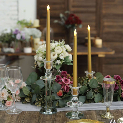 Elegant wedding table centerpiece with gold candles, flowers, and glassware