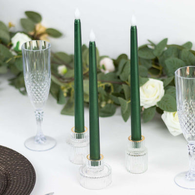Green taper candles in clear glass holders with champagne flutes and white roses