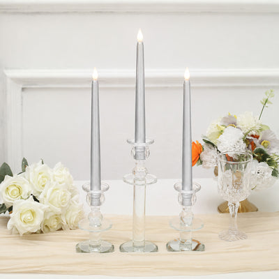 Elegant silver taper candles in clear glass holders with floral decor arrangement
