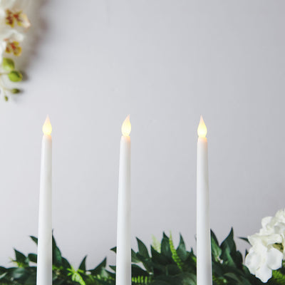 Three white candles with flickering flames against a soft background.