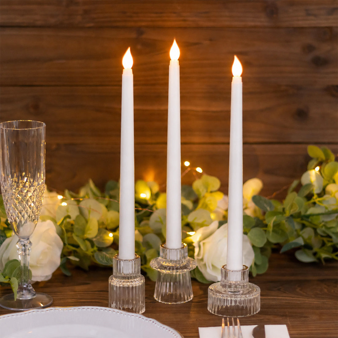 Elegant candlelit table setting with white taper candles and greenery
