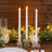 Elegant candlelit table setting with white taper candles and greenery
