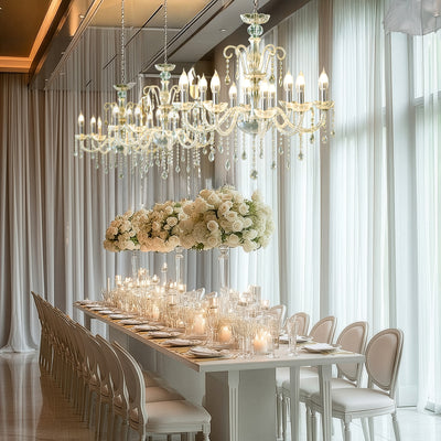 Elegant dining setup with chandeliers and floral centerpieces in a luxurious setting.