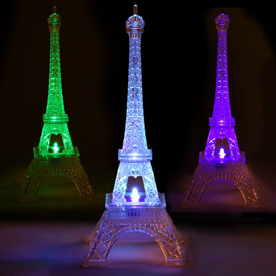 Colorful illuminated Eiffel Tower figurines in green, blue, and purple light.
