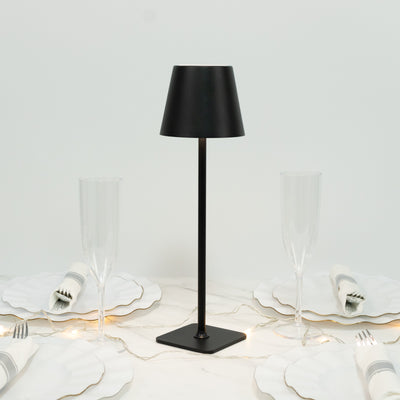 Black table lamp with modern design, set on a dining table with elegant glassware.
