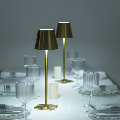 Elegant table setting with gold lamps and glassware, creating a warm ambiance.
