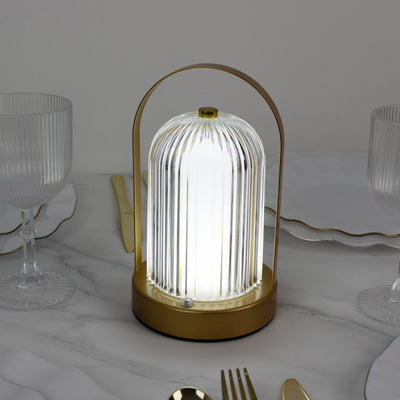 Elegant table lamp with a gold base and glass shade, illuminated softly.