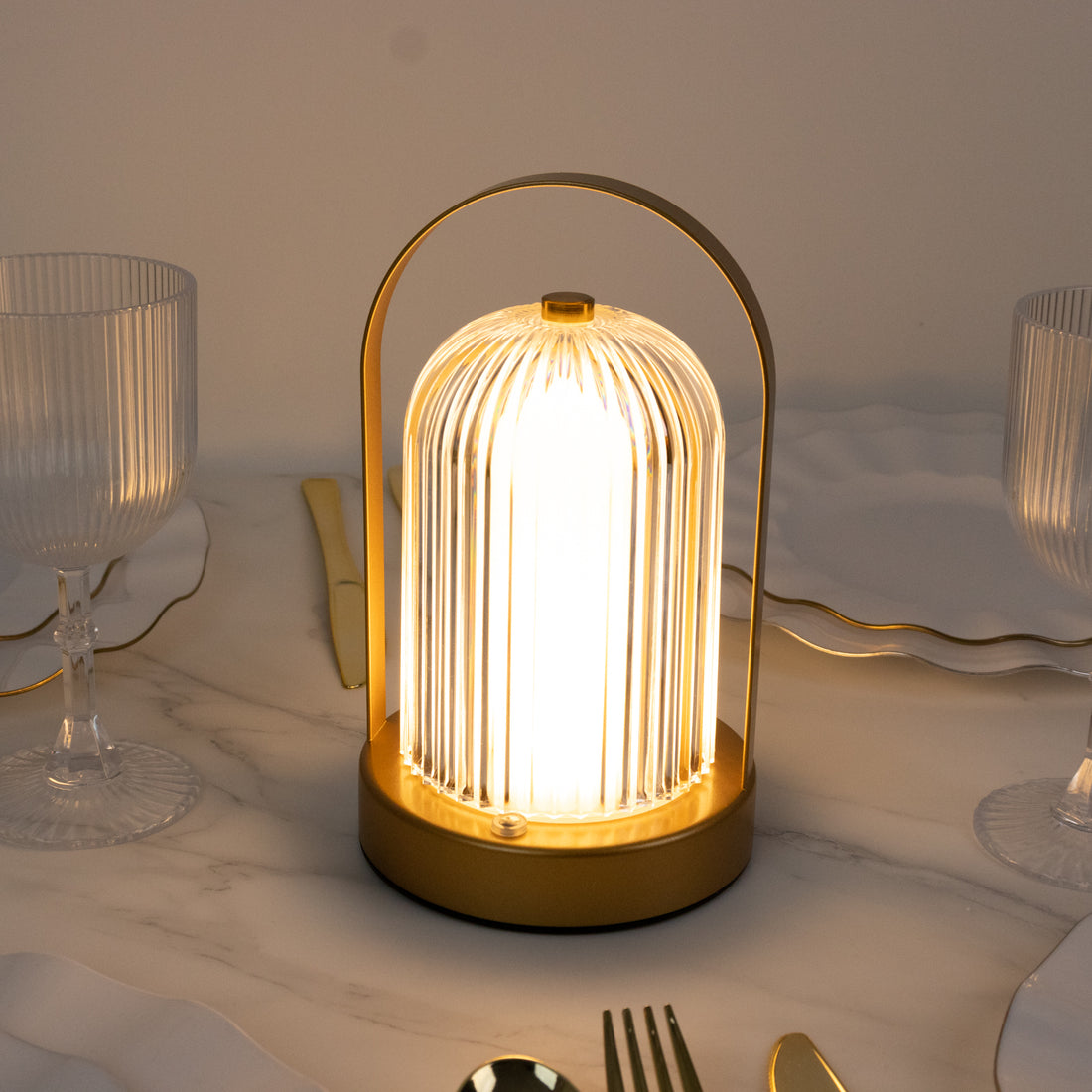 Stylish table lamp with a gold base and ribbed glass shade illuminating a dining setting.