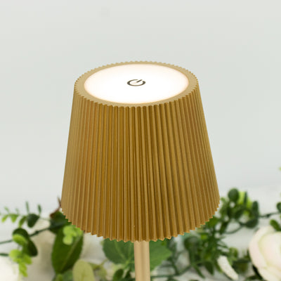 Gold ribbed table lamp with power button on top.