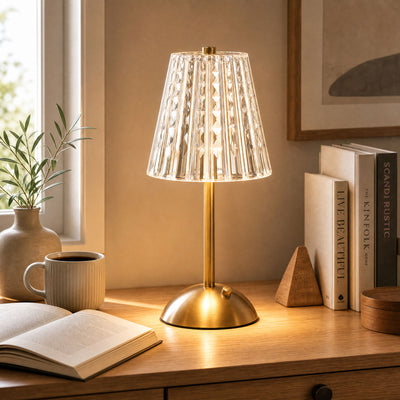 Brass crystal table lamp on wooden desk with books and coffee mug