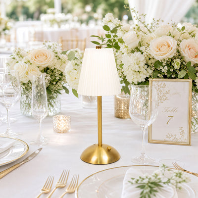 Elegant white and gold wedding table with floral centerpiece and table lamp
