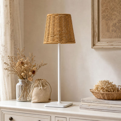 Rustic wicker table lamp on cream dresser with dried flowers and neutral decor
