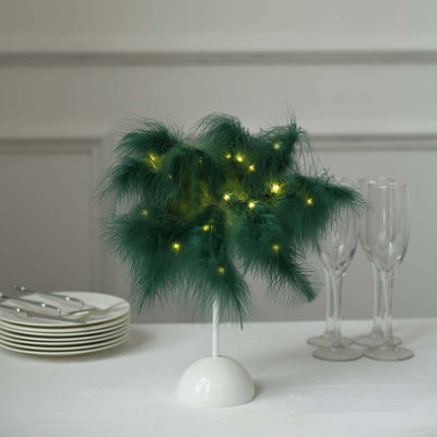 Decorative green lighted plant centerpiece with white base and elegant glassware.
