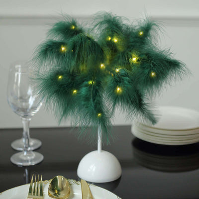 Decorative green feather tree with lights on a dining table