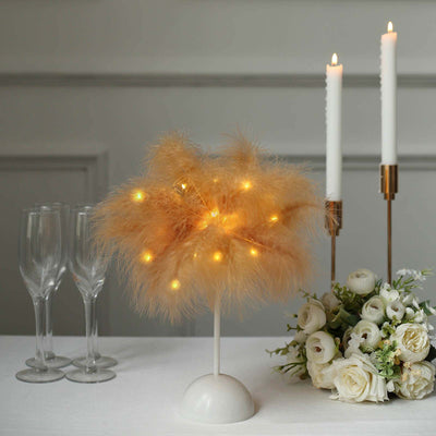 Decorative lit centerpiece with pampas grass, candles, and floral arrangement.