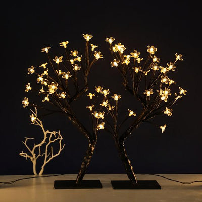Illuminated flower tree lamp with decorative branches against a dark background.