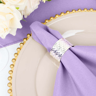 Purple napkin with silver napkin ring on an elegant dinner plate.