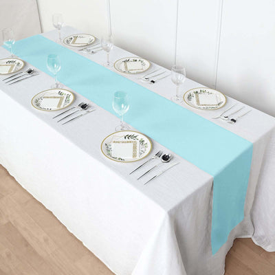 Table setting with a light blue runner and elegant plates.
