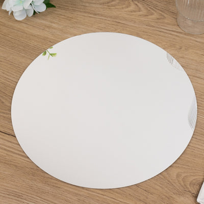Round decorative mirror with floral accents on a wooden table.