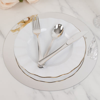 Elegant silver and white dinnerware set with utensils on a marble surface.