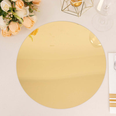 Gold round mirror placemat on a white table setting with flowers.