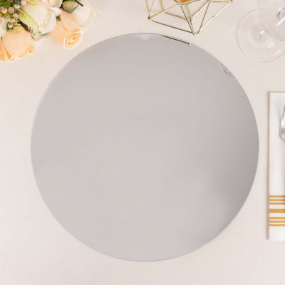 Round silver mirror plate on a table with flowers and decorative accents.