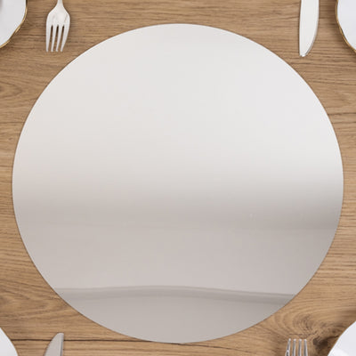 Round mirrored table centerpiece on a wooden dining table.