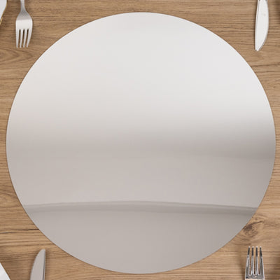 Round reflective serving platter on a wooden table with silverware.