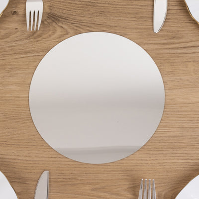 Round stainless steel placemat on a wooden table.