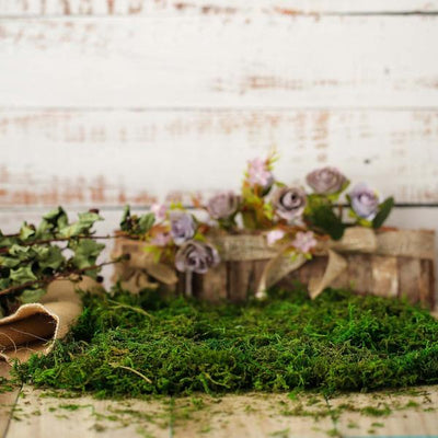 Decorative moss with flowers and greenery on rustic wood background.
