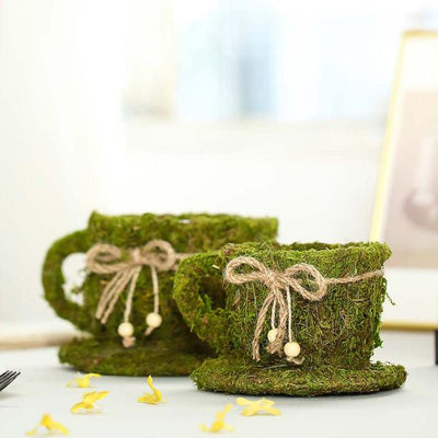 Moss-covered mugs with twine bows on a table