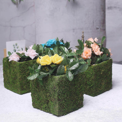 Artificial flower arrangements in moss-covered pots.