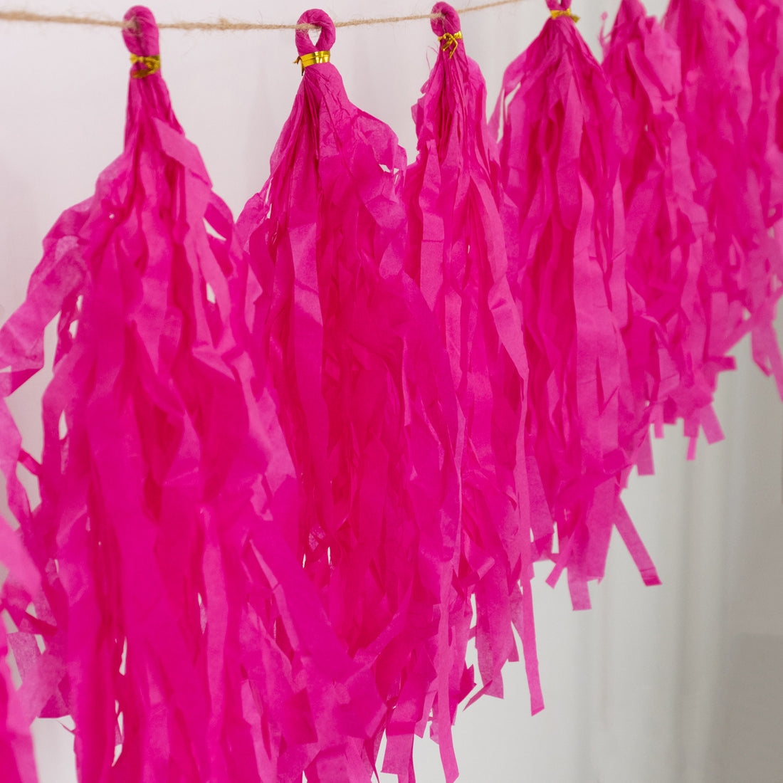 Pink party tassels hanging on a string for festive décor.