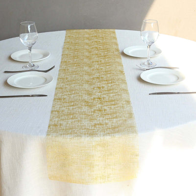 Elegant gold table runner on a round table set for dining.