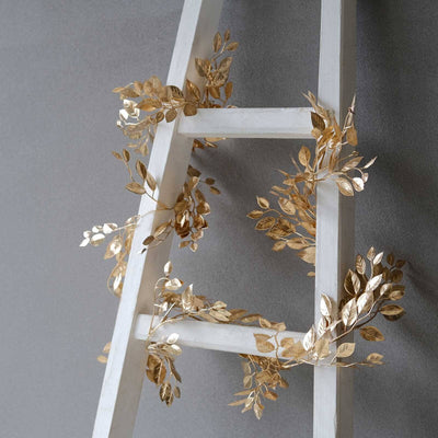 Gold leaf accents on a white ladder against a gray wall.