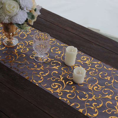Elegant gold floral table runner on rustic wooden table with candles and vase.
