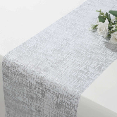 Silver textured table runner with floral arrangement on a white surface.